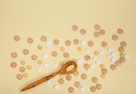 Spoon filled with pills and capsules. Vitamins and supplements on pink background.の写真素材
