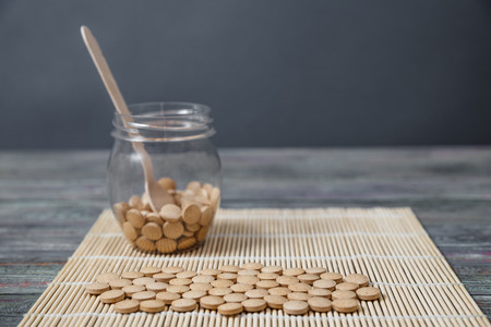 Alternative medicine tablets on a wooden spoon with a copy of spaceの写真素材