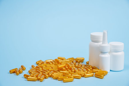 Golden pill capsules on blue background. Concept of expensive medical care or diagnosis.