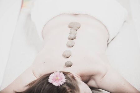 Beautiful girl in spa salon. Adult woman having hot stone massage in spa salon. Beauty treatment concept.の写真素材