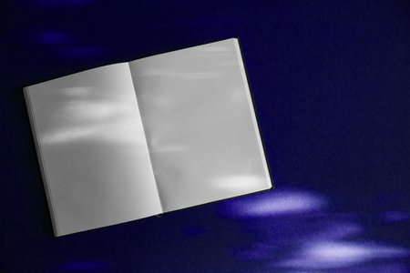 An open book on a table with spots of sunlight. Copy space