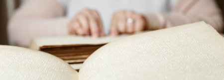 close up view of woman reading braille text on old book