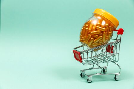 Medicines in shopping cart on blue background. The concept: trade in medicines, pharmacies. Copy space for text.の写真素材