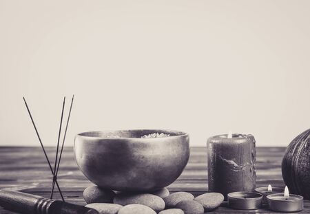 Singing bowl with candles with pebbles on dark wooden background with copy space.の写真素材