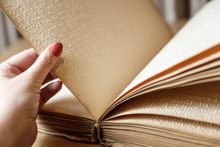 close up view of woman reading braille text on old bookの写真素材