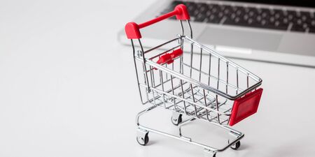 Online shopping. Bank card nearby a laptop and mini shopping cart on white background top view.の写真素材
