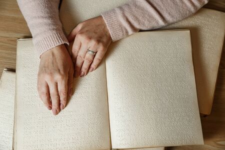 close up view of woman reading braille text on old bookの写真素材
