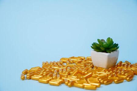 Golden pill capsules on blue background. Concept of expensive medical care or diagnosis.の写真素材