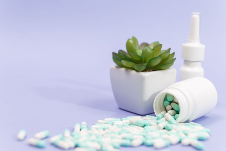 Blue and white capsules pill spilled out from white plastic bottle container. Global healthcare...