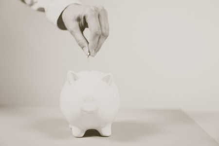Hand putting coin into piggy bank closeup. Selective focus. Piggy Bank, Savings, Currency.