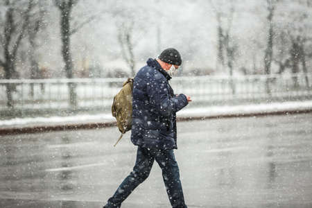 KYIV, UKRAINE - MARCH 22: A man wearing a protective mask as a precaution against the outbreak of Coronavirus during snowfall March 22, 2020 in Kyiv, Ukraine.のeditorial素材