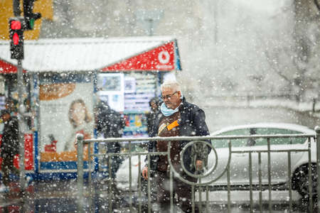 KYIV, UKRAINE - MARCH 22: A man wearing a protective mask as a precaution against the outbreak of Coronavirus during snowfall March 22, 2020 in Kyiv, Ukraine.のeditorial素材