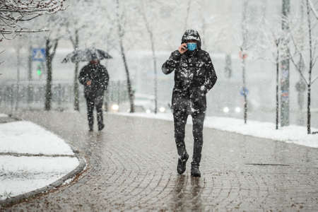 KYIV, UKRAINE - MARCH 22: A man wearing a protective mask as a precaution against the outbreak of Coronavirus during snowfall March 22, 2020 in Kyiv, Ukraine.のeditorial素材