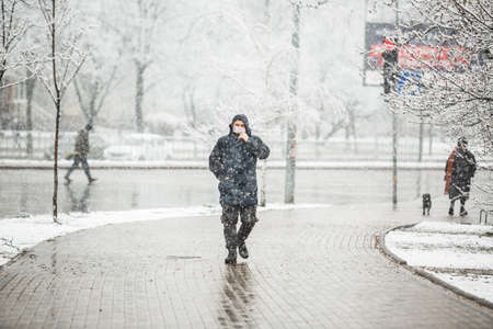 KYIV, UKRAINE - MARCH 22: A man wearing a protective mask as a precaution against the outbreak of Coronavirus during snowfall March 22, 2020 in Kyiv, Ukraine.のeditorial素材
