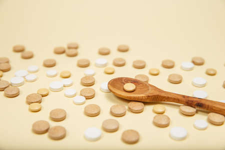 Spoon filled with pills and capsules. Vitamins and supplements on pink background.の写真素材