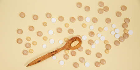 Spoon filled with pills and capsules. Vitamins and supplements on pink background.の写真素材
