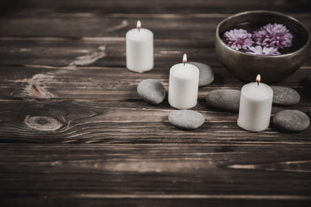 Singing bowl with candles with pebbles on dark wooden backgroundの写真素材