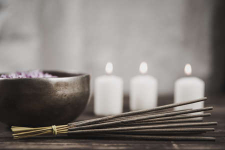 Singing bowl with candles with pebbles on dark wooden backgroundの写真素材