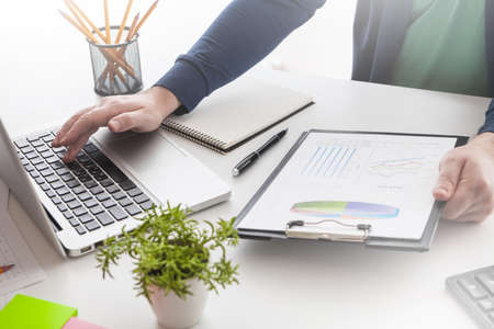 Businessman holding a pen is working with graph documents and sunset light background. Stock market chart and finger pointing on tablet in office.の写真素材