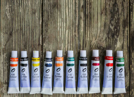 Paint tubes, brushes for painting and palette knifes on old wooden background.の写真素材