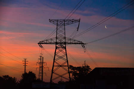 Electrical lines under a night sky with moon. power electric line and transmission towerの写真素材