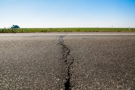 Old asphalt road. Driving on an empty road. Cracked white line on the asphalt road. Shallow depth of field.の写真素材