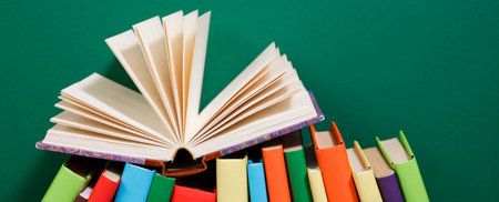 Composition with vintage old hardback books, diary, fanned pages on wooden deck table and colored background. Books stacking. Back to school. Copy Space. Education background.の写真素材