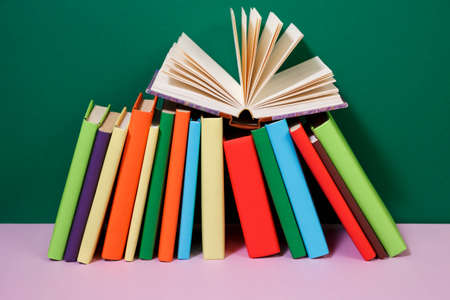Composition with vintage old hardback books, diary, fanned pages on wooden deck table and colored background. Books stacking. Back to school. Copy Space. Education background.の写真素材