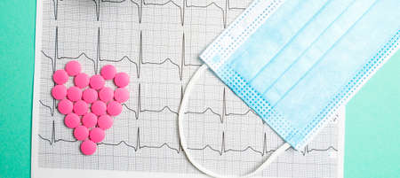 A pile of red pills in a shape of heart on cardiogram. Medical concept.の写真素材