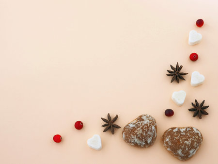 Ginger bread hearts upon pink background with anise stars and fresh cranberries. Top view. Copy...