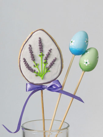 Easter hand held cookie and small eggs in a glass. Easter theme. Homemade sugar cookies in the shape...