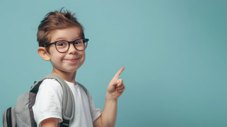 cute happy child school boy with backpack looking at camera on pastel blue background,の素材