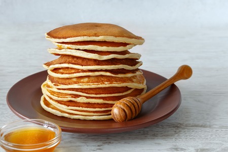 Stack of pancakes in a plate on the table, light backgroundの写真素材