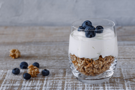 Granola with yogurt and blueberries in a glass beaker on a wooden backgroundの写真素材
