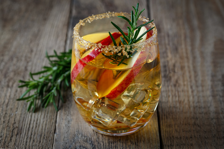 Apple drink in a glass with apple slices and rosemary on a wooden backgroundの写真素材