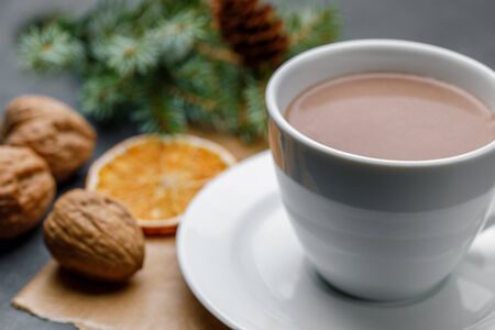 White cup with cocoa on a Christmas background with walnuts, an orange slice, with shallow depth of fieldの写真素材
