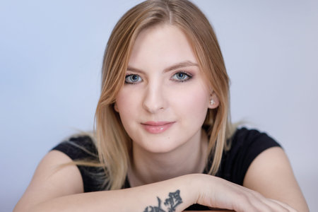 Close-up face of a young girl with delicate make-up and tattoo on her arm