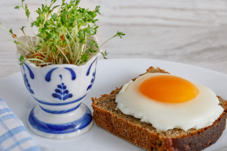 Fried eggs on a piece of whole-grain rustic bread with a salad dressing in an egg stand