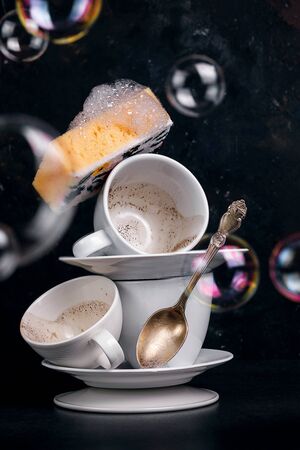 Washing coffee cups with a washcloth with foam, conceptual photo with soap bubblesの写真素材