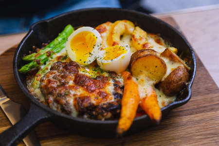 Fried pork with asparagus and egg in a small pan, served in a street cafeの写真素材