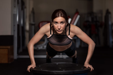 Young woman doing push-ups in the gym on a balancing hemisphere.の写真素材