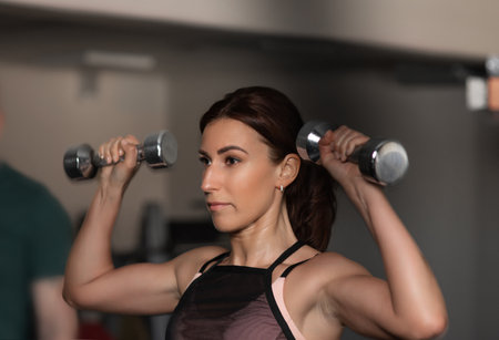 Sports woman, sportswoman with dumbbells is engaged in fitness on the background of the gymの写真素材