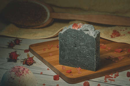 Still life with one piece of handmade soap and bath salt on a wooden board. Focus on a bar of soap.の写真素材