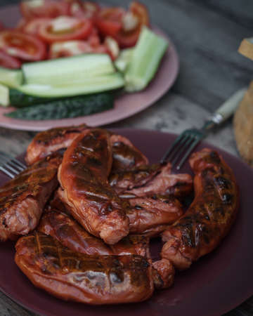 Hot sausages with grill close-up. Serving option with cutting vegetables on a wooden table.の写真素材