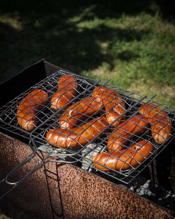 Hot fried sausages in the grill. Cooking on charcoal in the grill.の写真素材