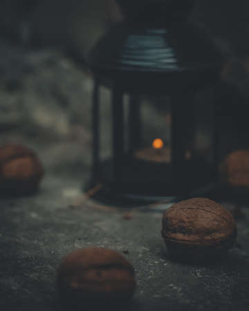 Close-up of a flashlight with a burning candle surrounded by walnuts. Dark photo at dusk. Style of film photography.の写真素材
