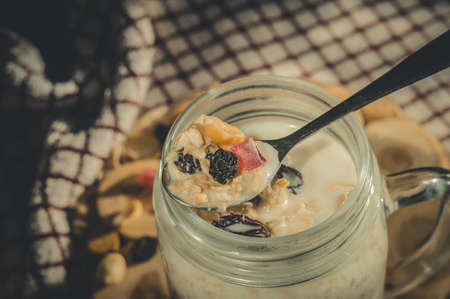 Glass jar with a healthy breakfast of oatmeal with nuts, dried fruits and yogurt. Early morning, top view, close upの写真素材