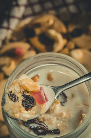 Glass jar with a healthy breakfast of oatmeal with nuts, dried fruits and yogurt. Early morning, top view, close upの写真素材