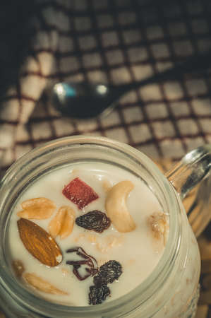 Glass jar with a healthy breakfast of oatmeal with nuts, dried fruits and yogurt. Early morning, top view, close upの写真素材