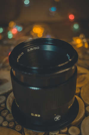 Soviet old lens with manual focus on a decorative wooden stand. Warm light. Side view, close upの写真素材